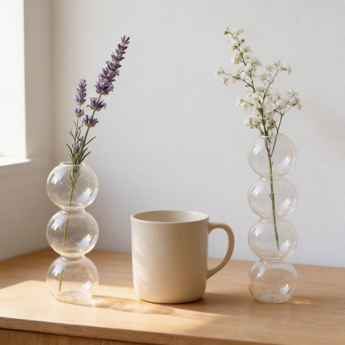 Clear small three-bubble and large four-bubble glass vases side by side with a mug, showing the two sizes.