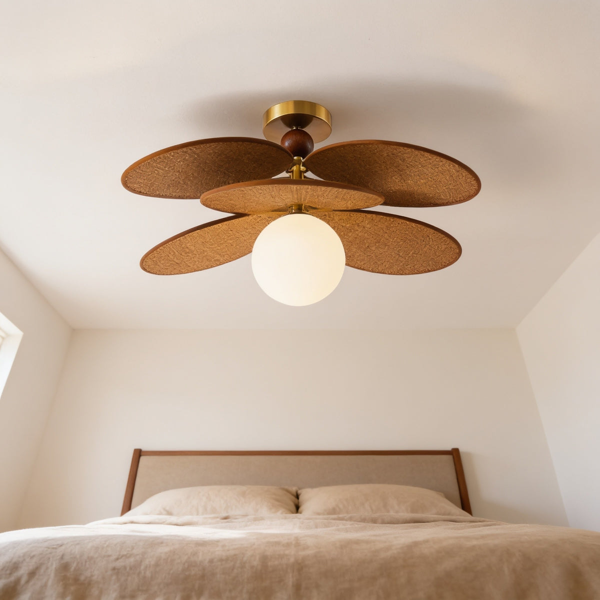 Single-globe woven leaf flush-mount ceiling light above a bed.