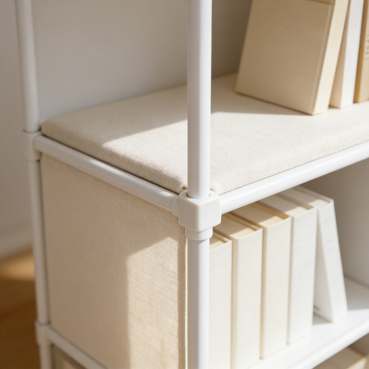 Close detail of the white steel tube frame, corner connector and fabric-covered shelf.