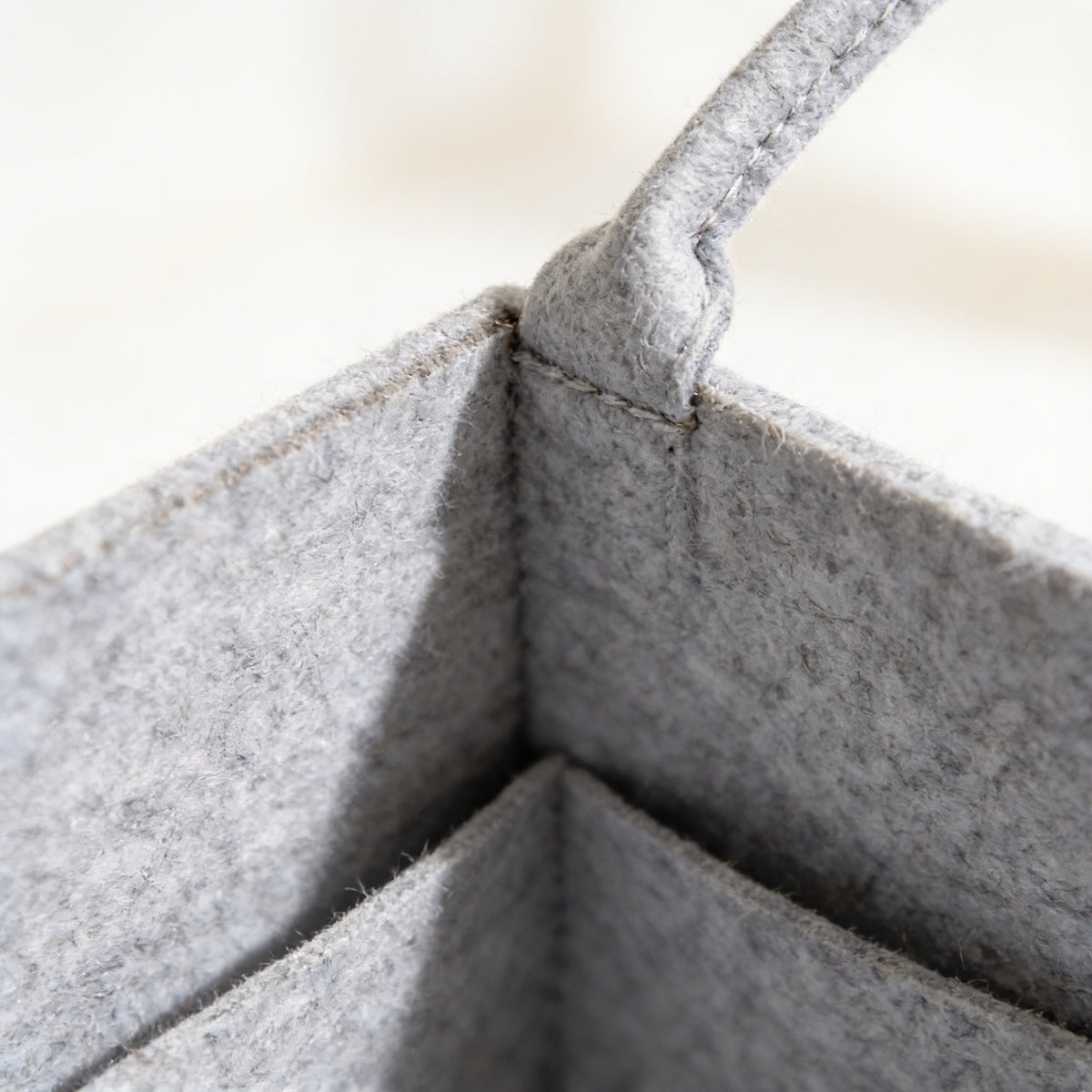 Close detail of the heathered gray felt and the stitched base of a felt handle.
