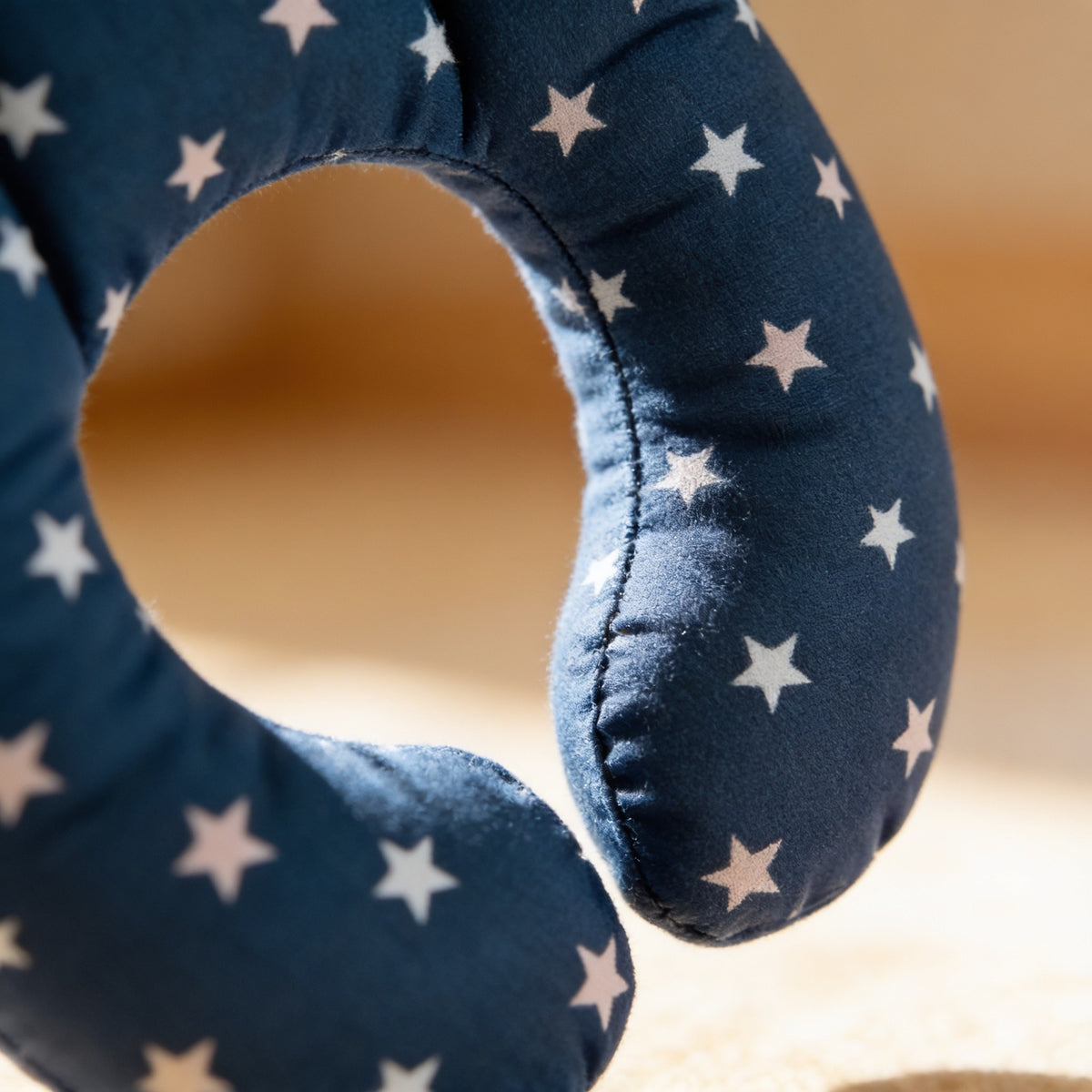 Close detail of the navy star cotton print and soft stitched seam of the neck pillow.