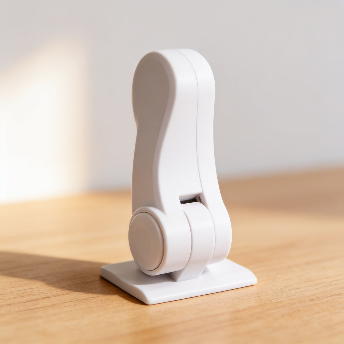 One white adhesive door lever lock standing upright on its base plate on a light oak surface