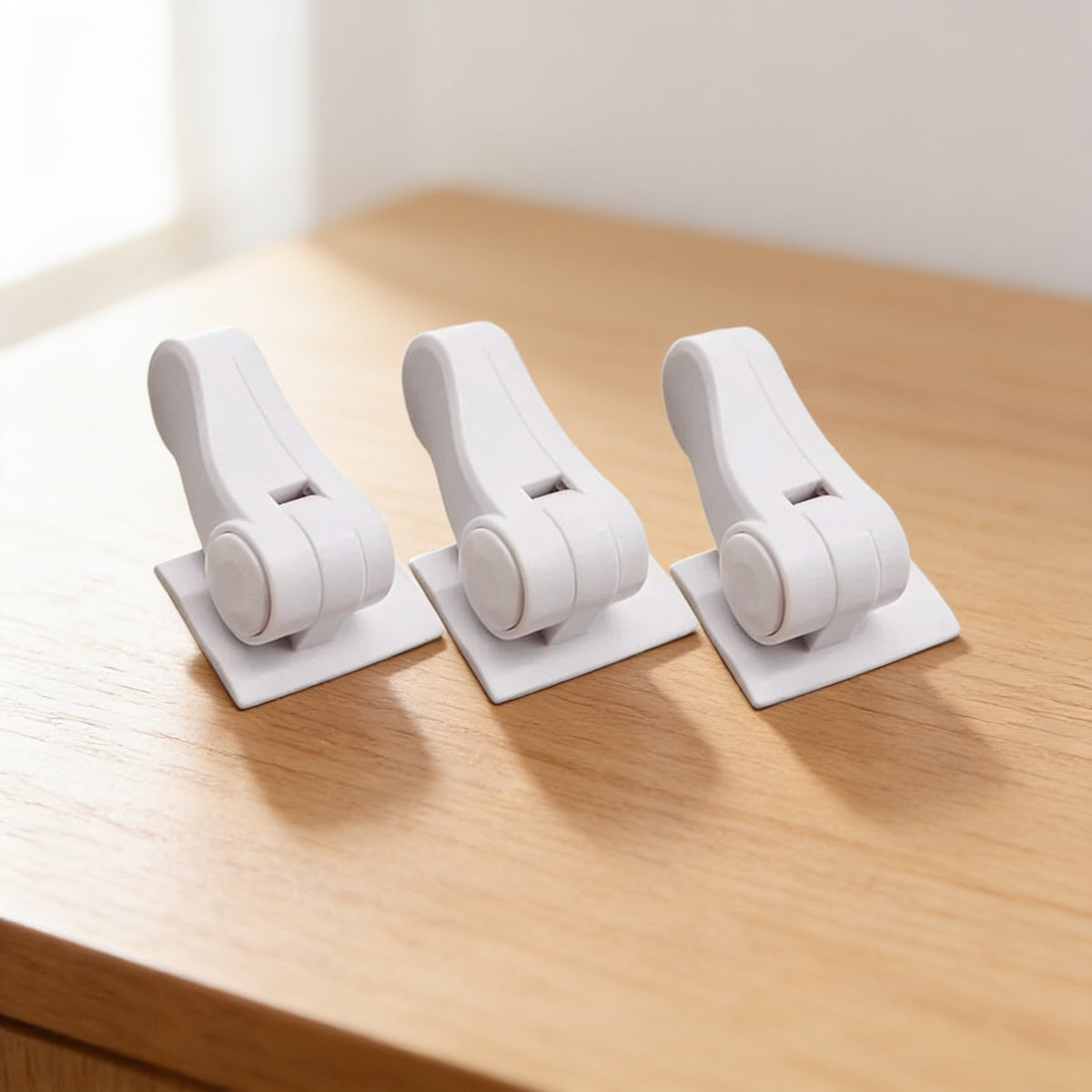 3-Pack of white adhesive door lever locks standing in a row on a light oak surface