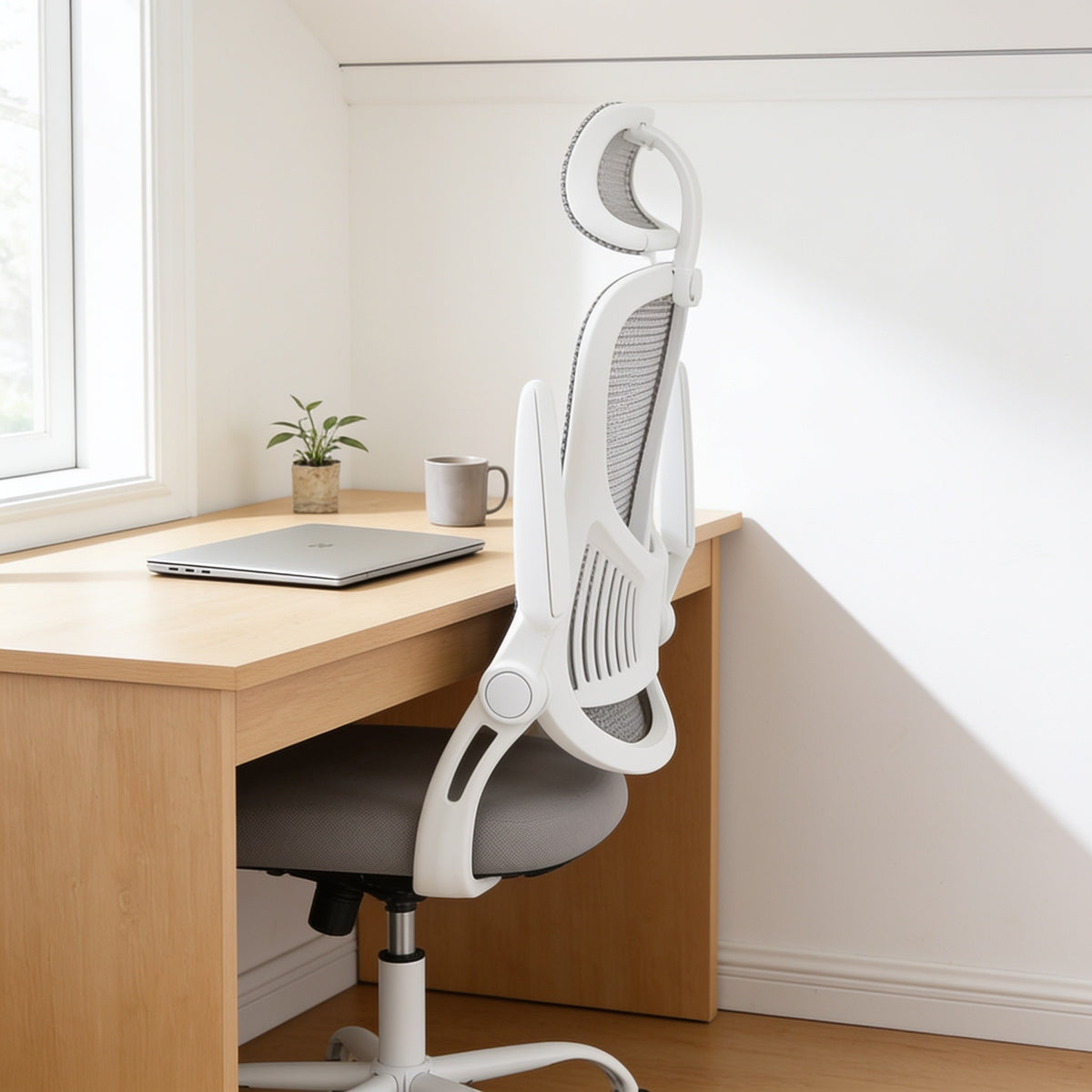 Mesh office chair with both armrests flipped up, tucked fully under the desk.