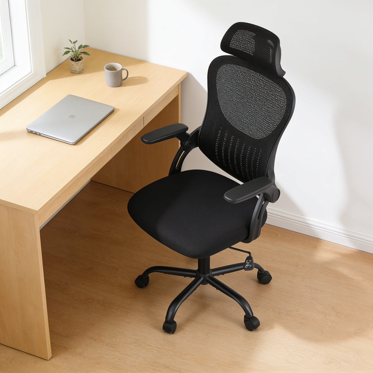 All-black mesh office chair with headrest and flip-up arms at a home office desk.