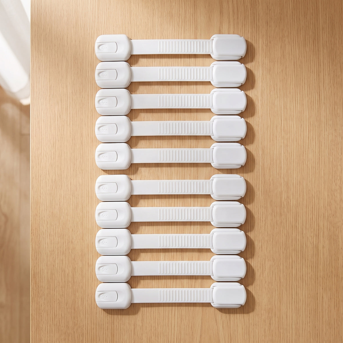 Ten white strap cabinet locks on a light oak kitchen countertop