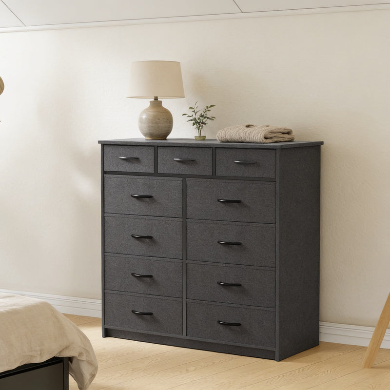 Black 9-drawer fabric dresser with steel frame in a calm bedroom, 100 cm wide and 100 cm tall, lamp and plant on top.