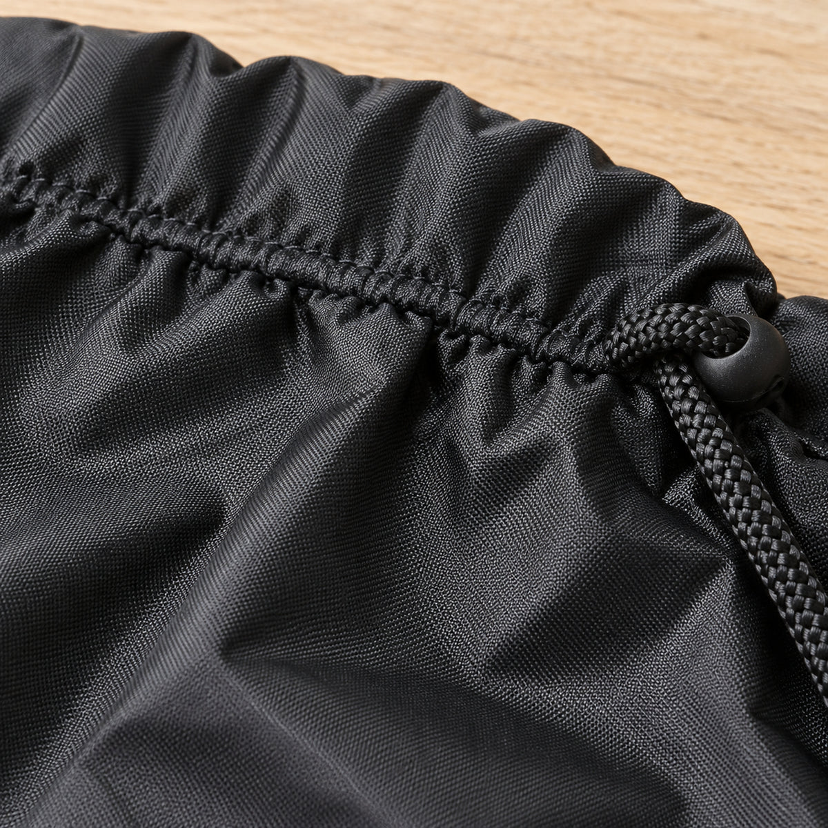 Close-up of black Oxford fabric, fine woven texture and stitching around the travel bag opening
