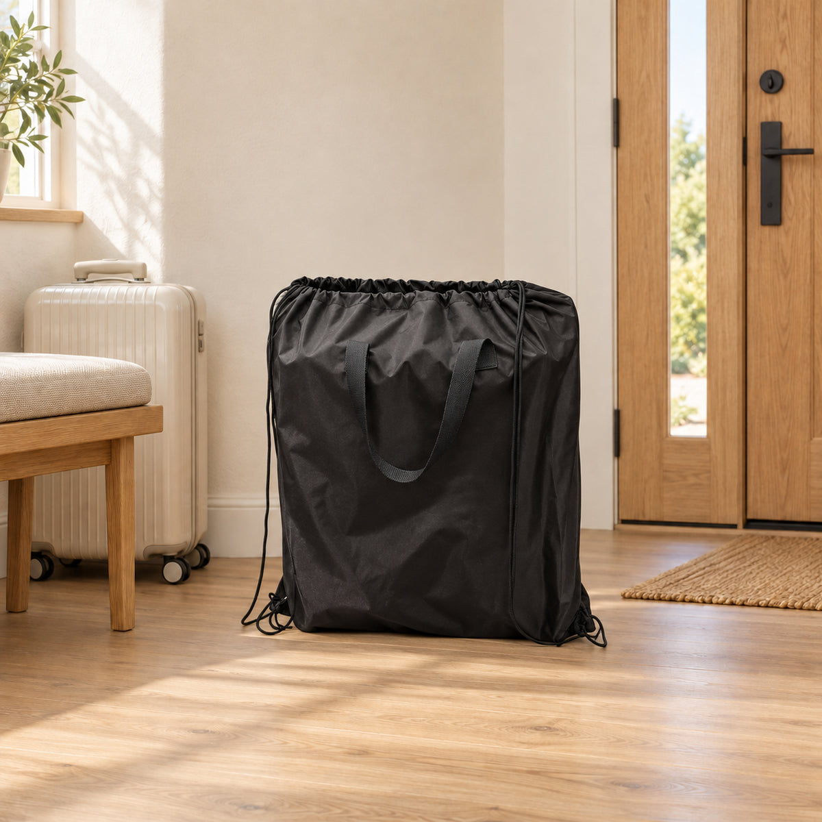 Black compact drawstring travel bag with fabric handles and long side cords in a warm entryway