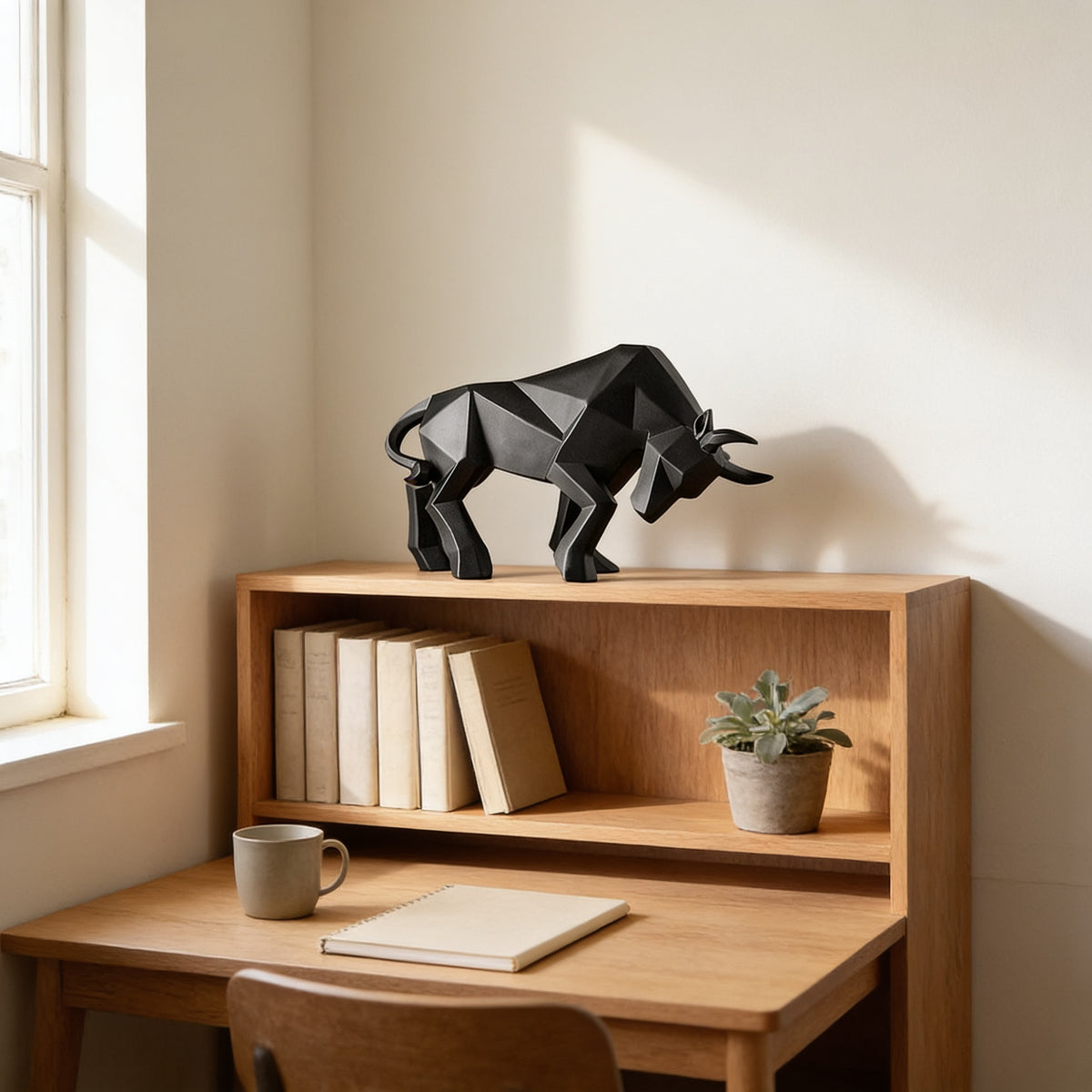 Black faceted bull statue on a low oak bookshelf beside a desk — Faceted Geometric Bull Statue
