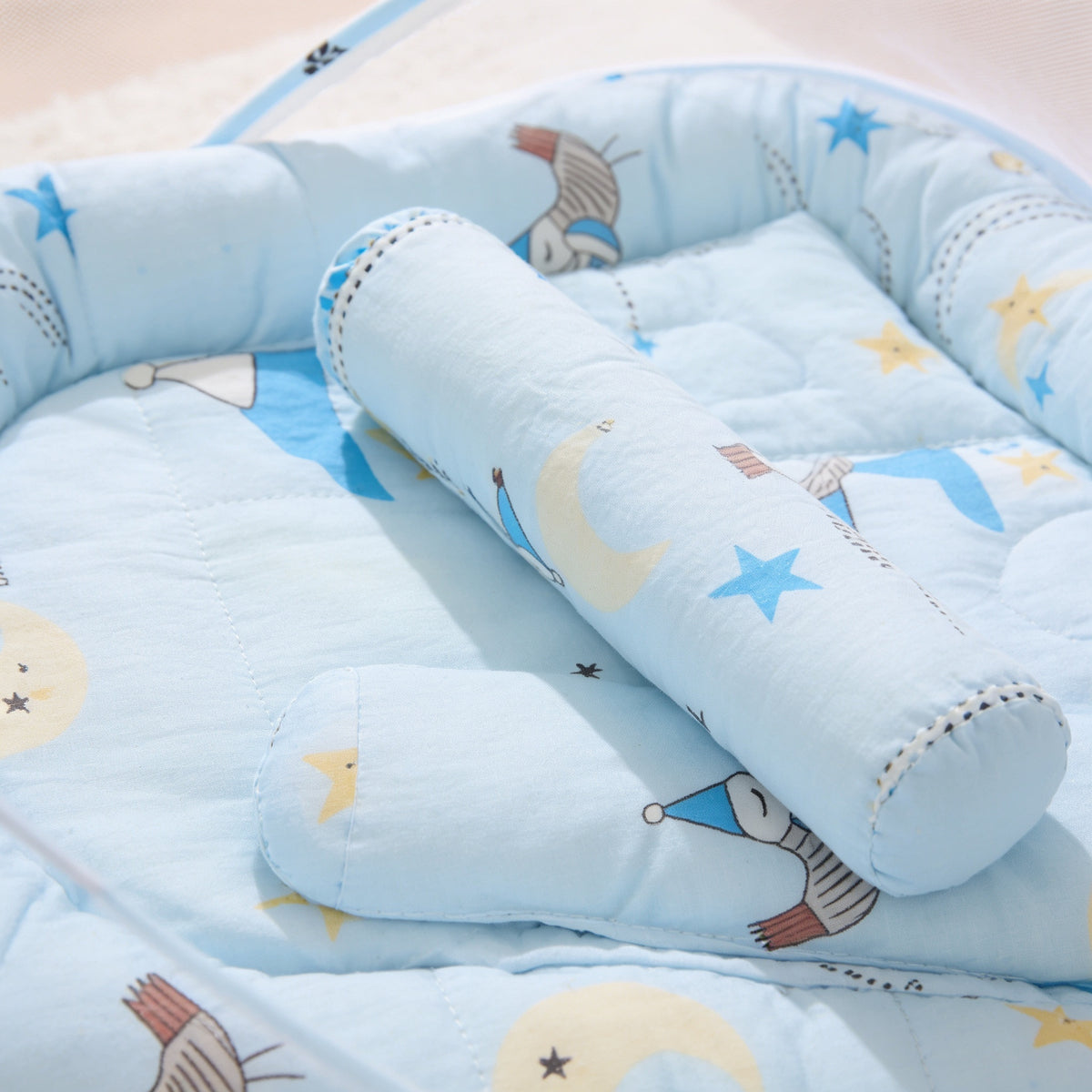 Close view of the quilted cotton pad and support roll of the Blue Storks travel bassinet print