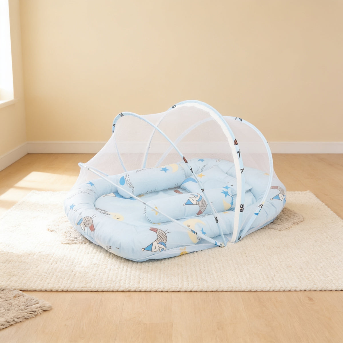 Blue Storks foldable travel bassinet, pale blue cotton with storks, moons and stars, with its mesh net dome up on a cream rug in a bright living room