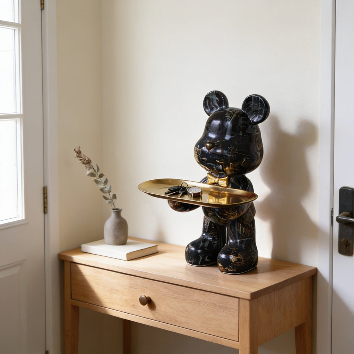 Black and gold marble graffiti bear statue holding a gold tray on an entryway console