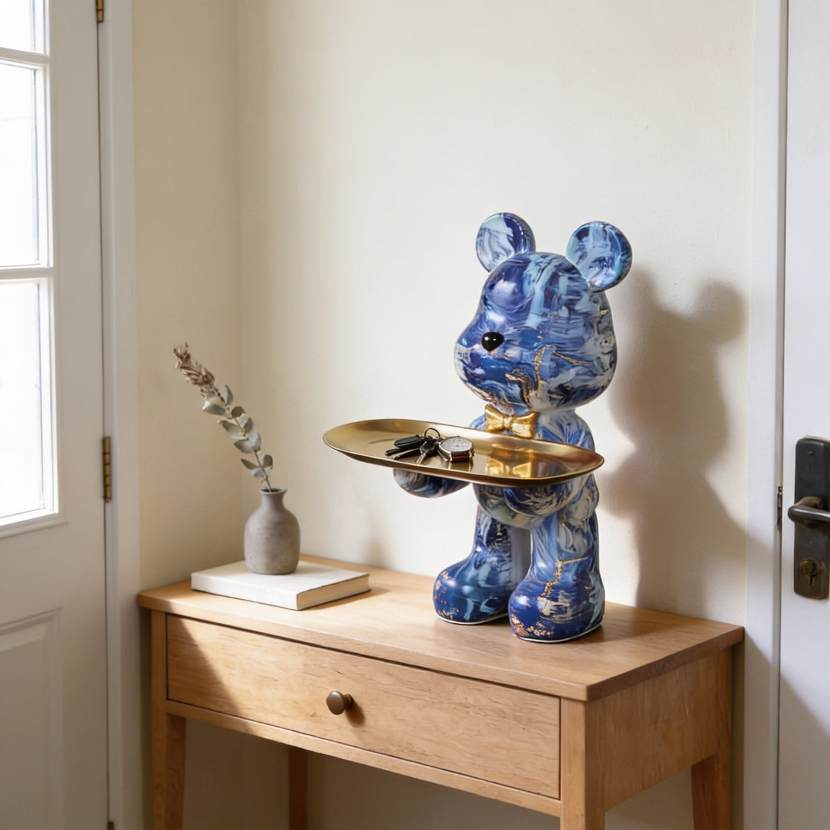Blue marble graffiti bear statue holding a gold tray on an entryway console