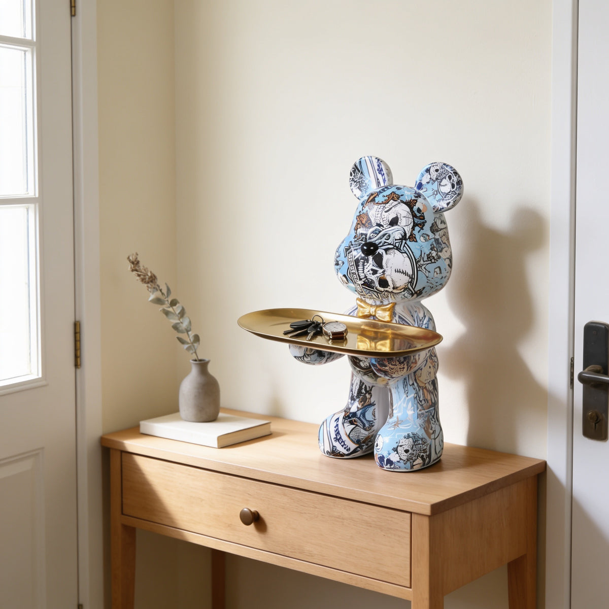 Monochrome graffiti bear statue holding a gold tray on an entryway console