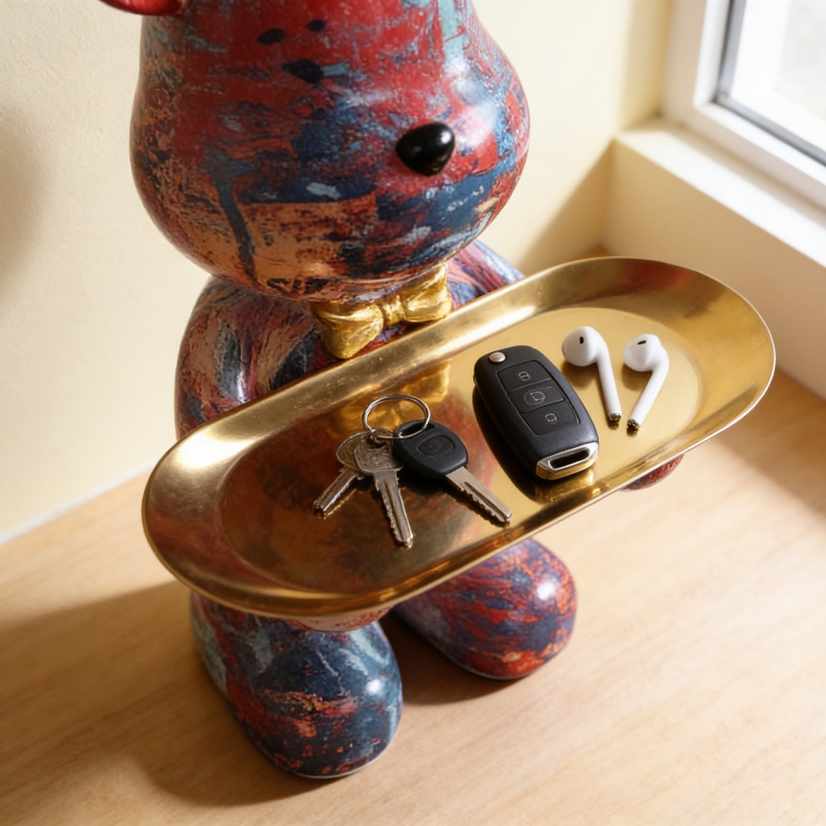 Gold tray on the graffiti bear statue holding keys and earbuds