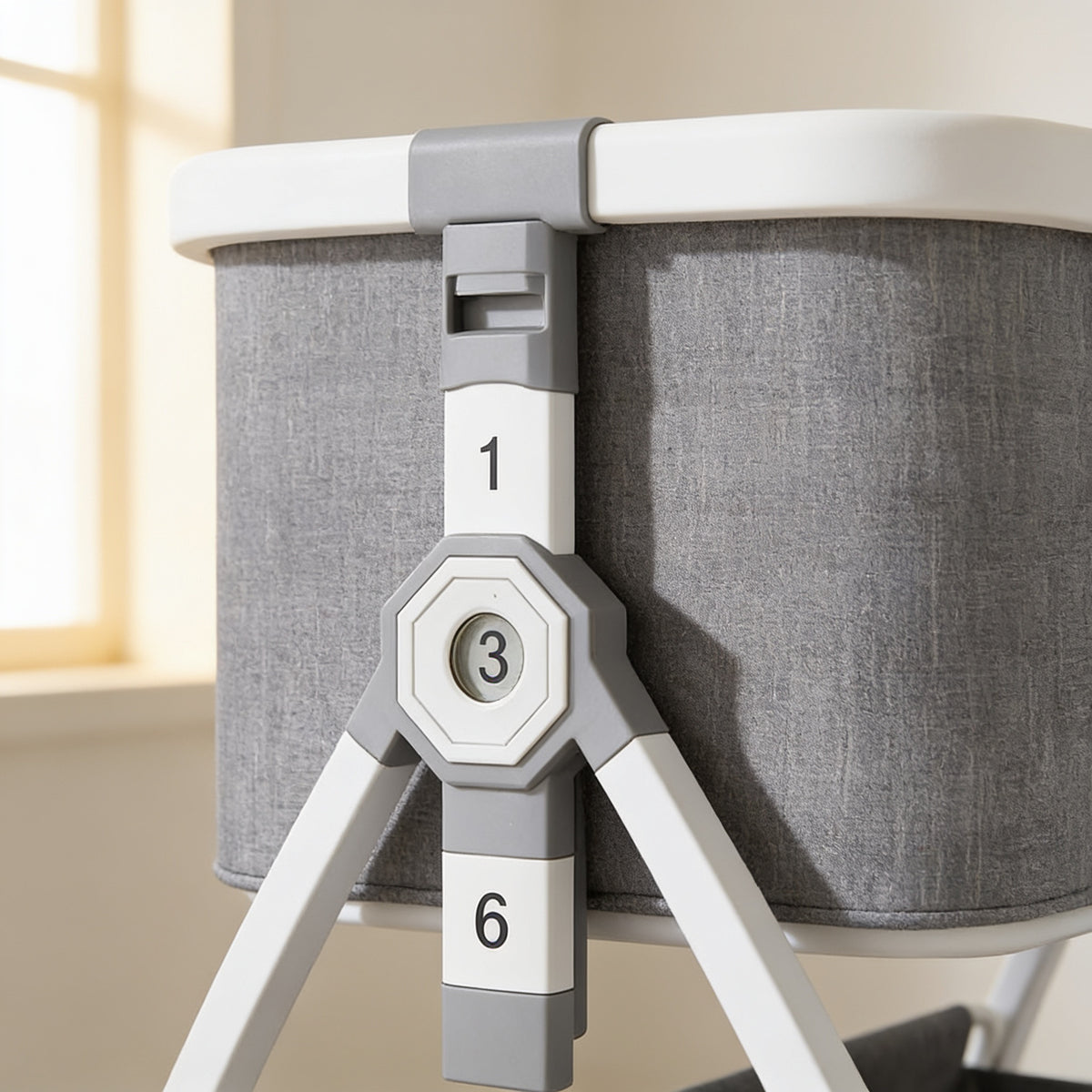 Close view of the bedside bassinet's height-adjustment column: grey rim clamp with finger slot, white segments printed 1 and 6, and the octagonal hub window showing gear 3, with white aluminium legs against the grey linen-look wall