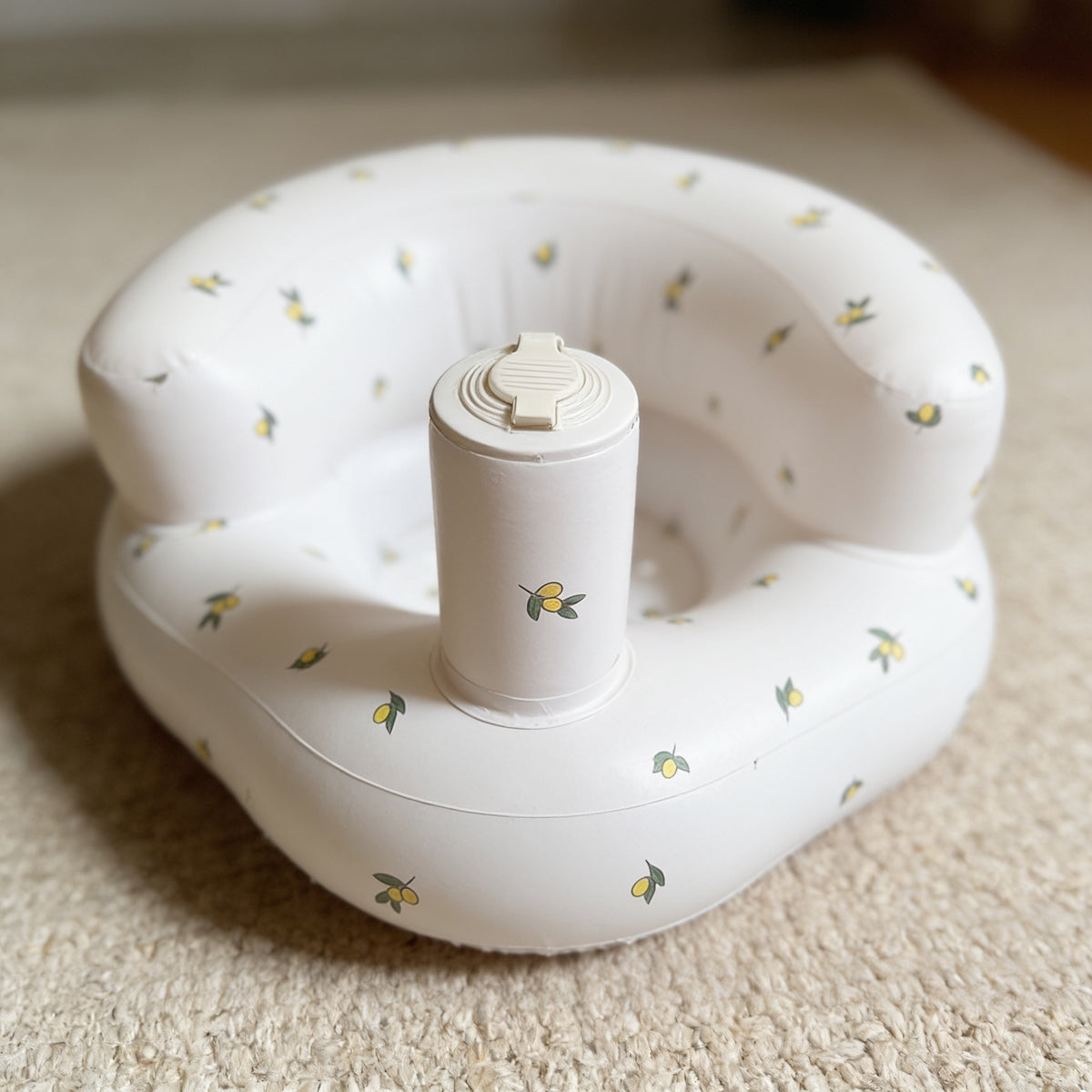 Close view of the built-in pillar pump on the Olive Flower inflatable baby seat, showing its ridged cream flip-tab valve cap