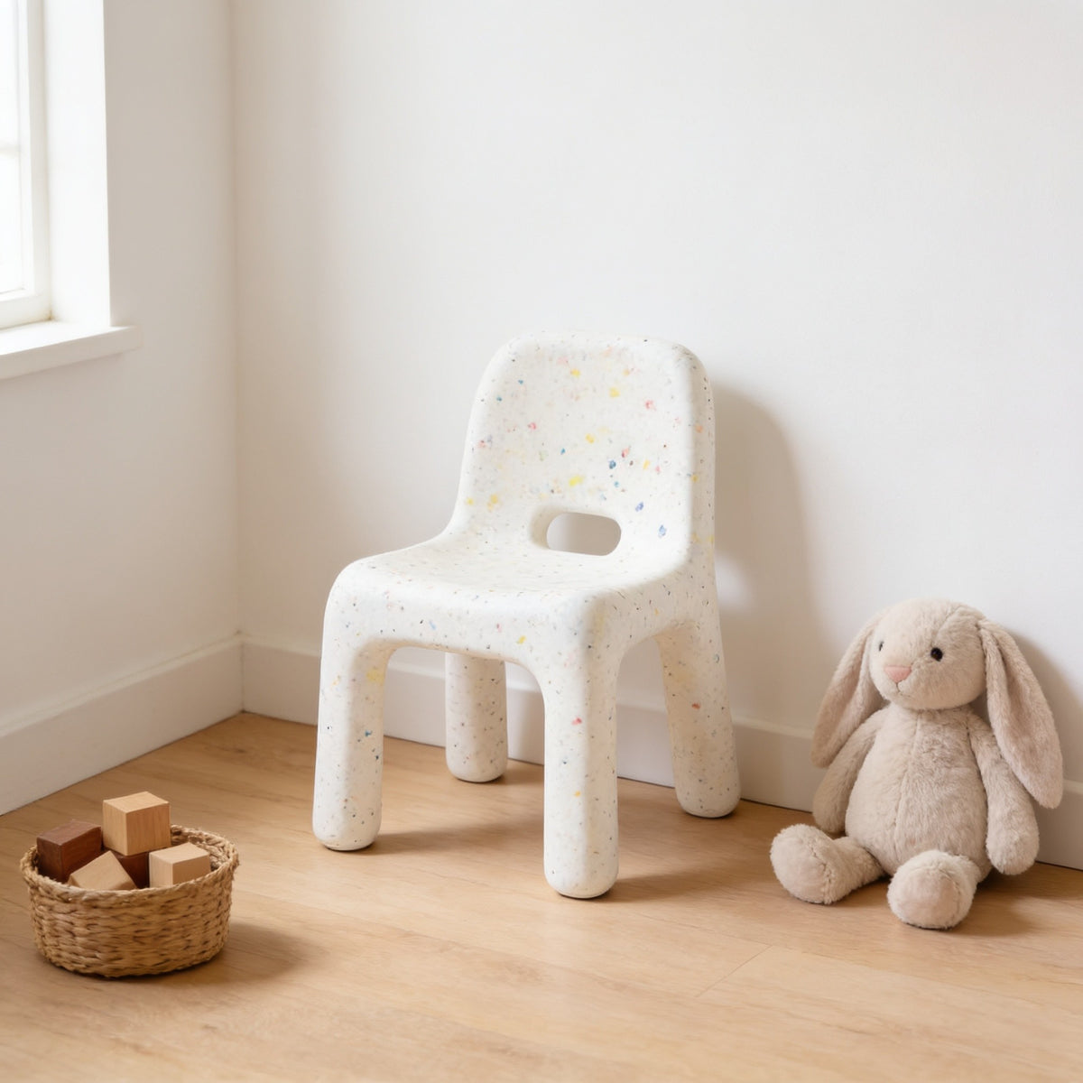 White speckled molded kids chair with a hand-hole backrest in a sunny kids room.