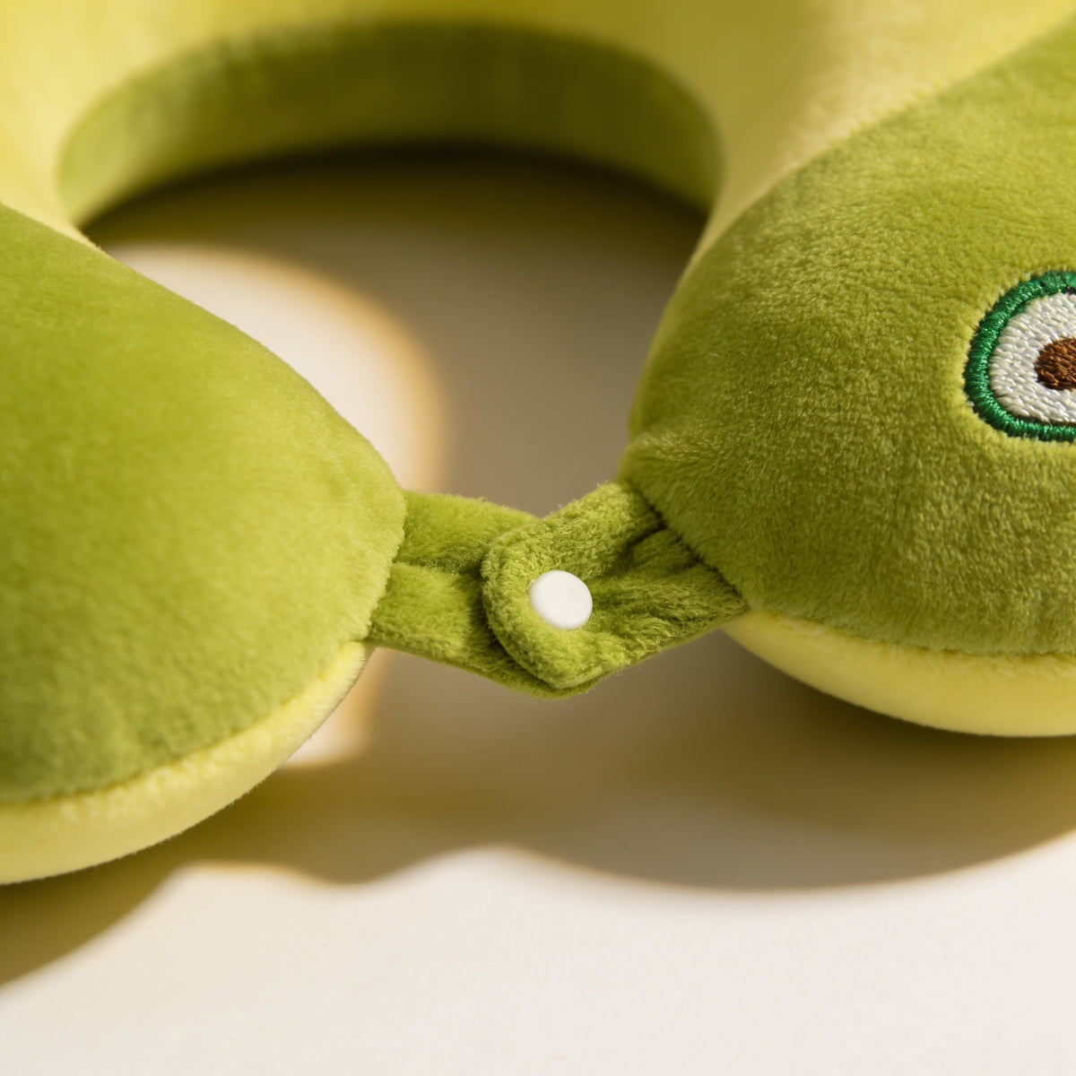 Close-up of the snap tab joining the two front ends of the green avocado travel neck pillow