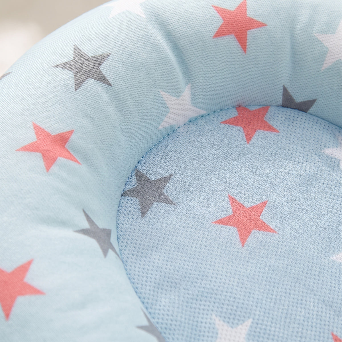 Macro of the breathable pale blue mesh centre panel meeting the soft padded star-print surround of the Blue Stars newborn bath cushion