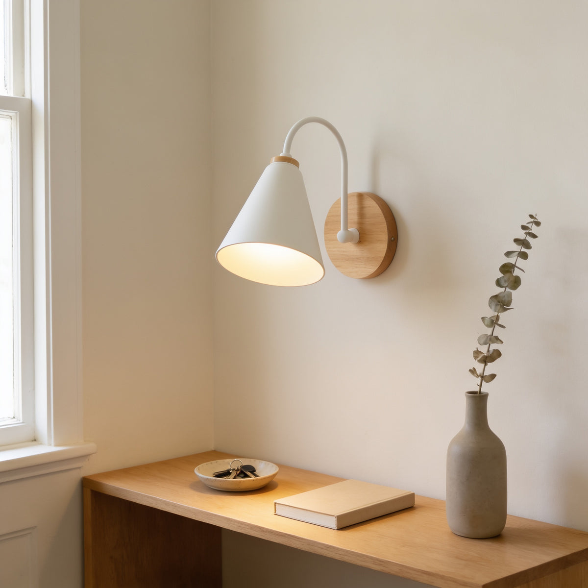 White cone wall sconce lighting an oak console with keys and a book in a hallway — Nordic Wood & Metal Cone Wall Sconce