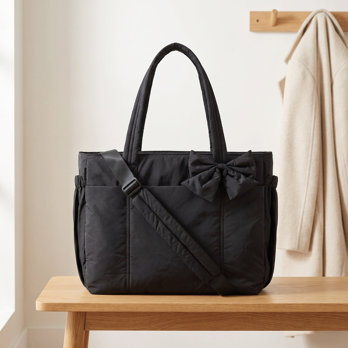 Black 15.6in puffer tote bag with its shoulder strap on an entryway bench