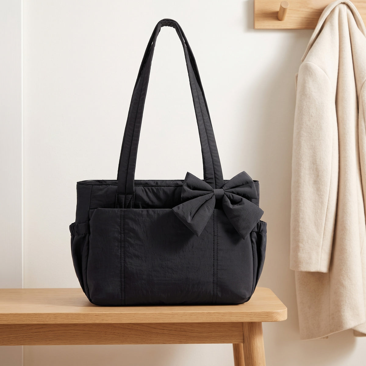 Black puffer laptop tote bag with a bow on an entryway bench