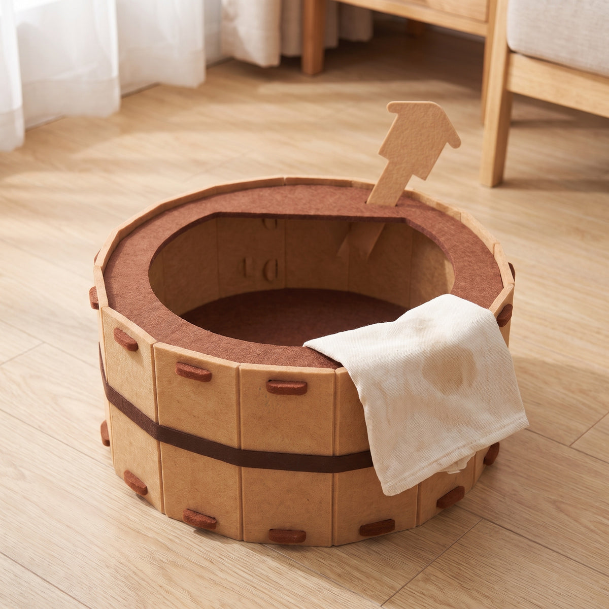 Felt cat bed standing empty with a cloth folded over the rim after a wipe down