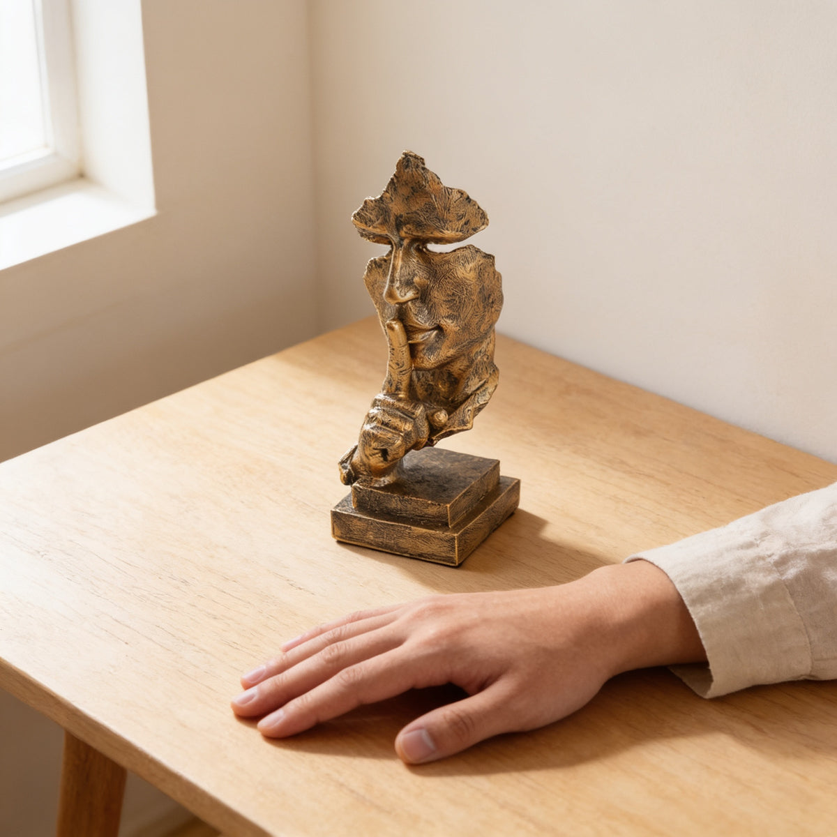 Antique gold thinker statue on an oak table next to a hand for scale — Silence Is Golden Thinker Statue