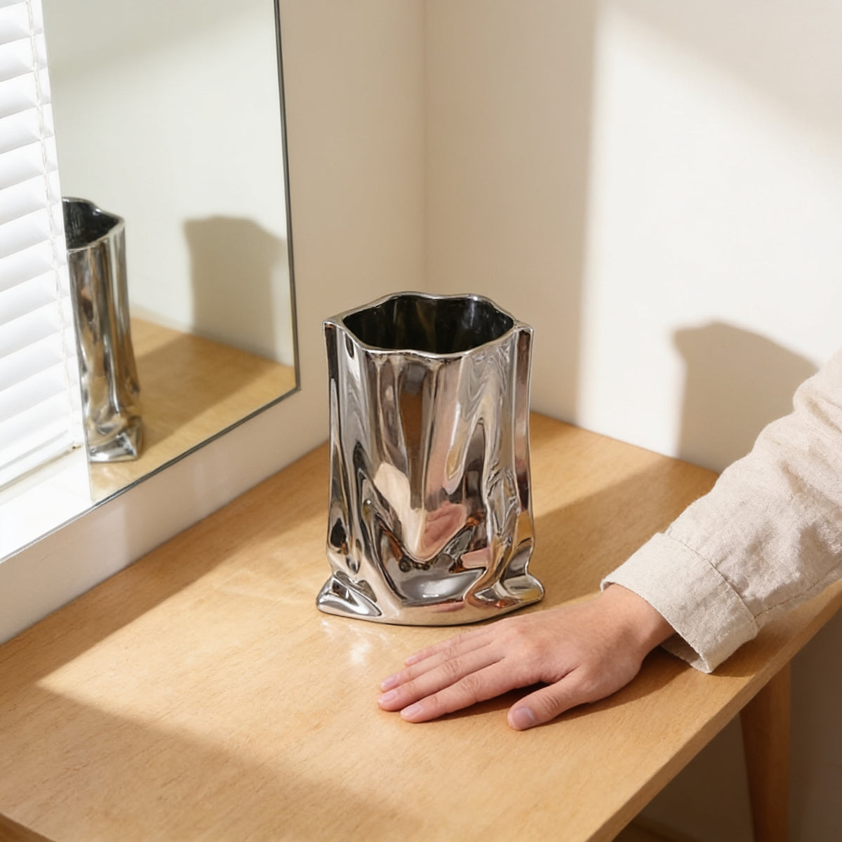 Silver crinkle vase, empty, on an oak table next to a hand for scale — Silver Crinkle Paper-Bag Vase