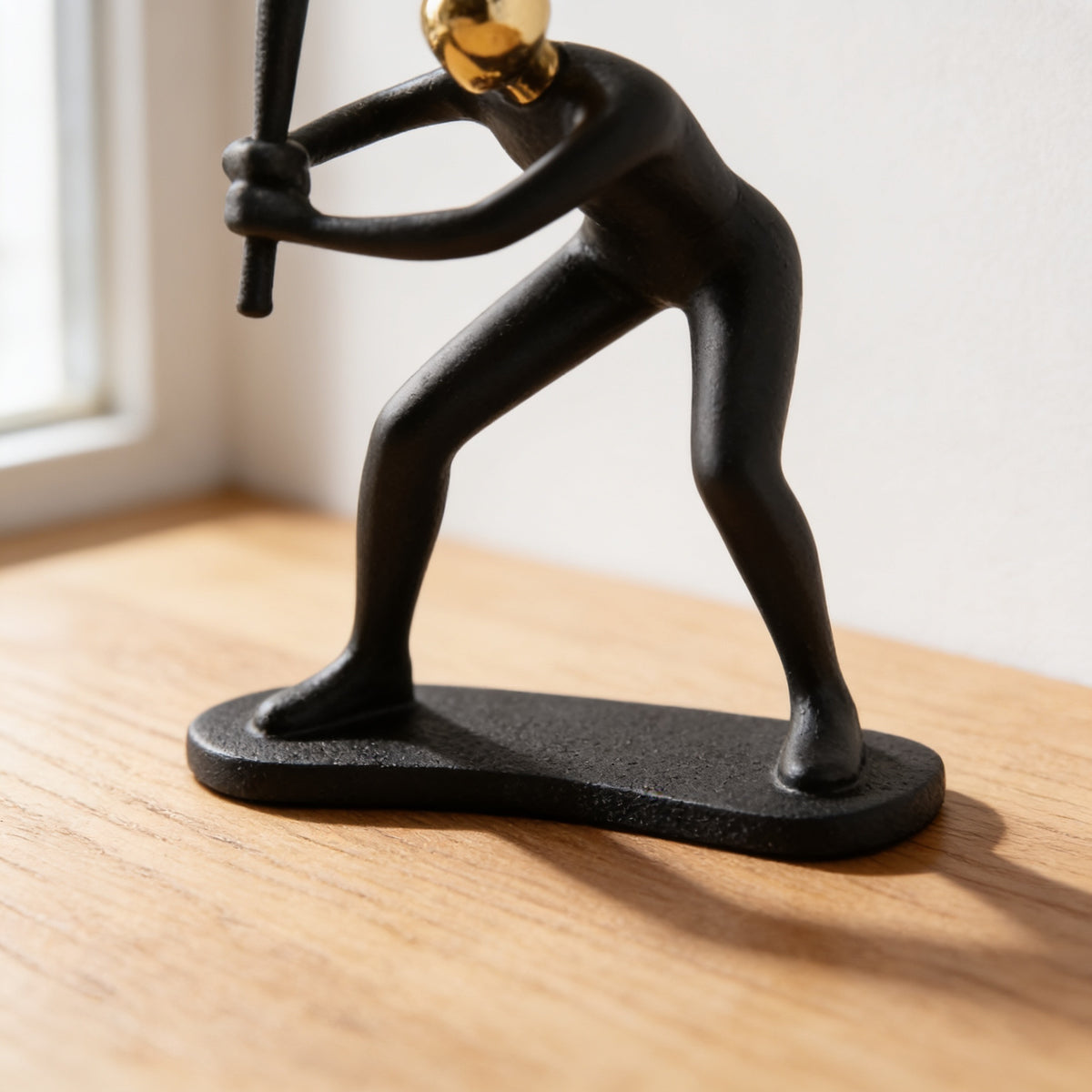 Detail of the flat matte black base standing on an oak surface — Black & Gold Sports Figurine