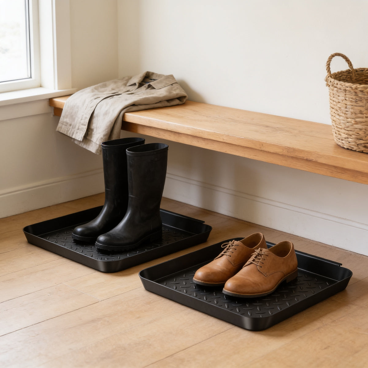 Textured boot trays under an entryway bench holding boots and shoes
