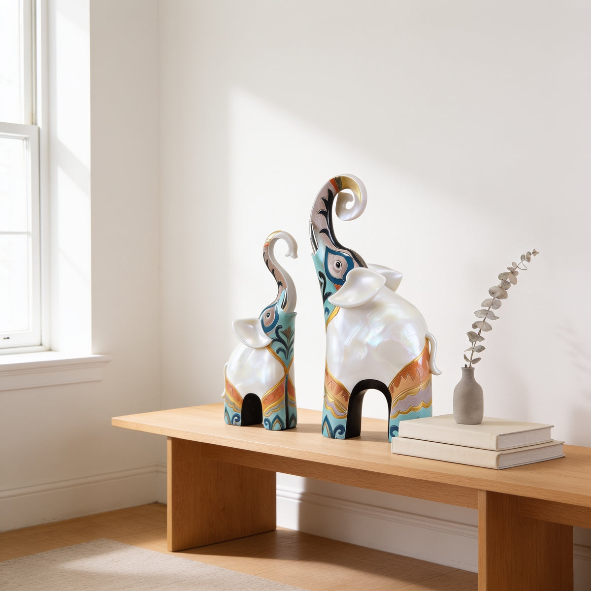 Mother and calf trunk-up elephant statues on an oak bench