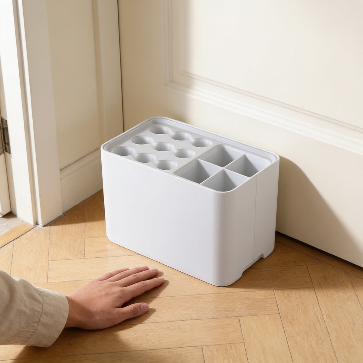 Hand beside the white umbrella stand showing its compact size