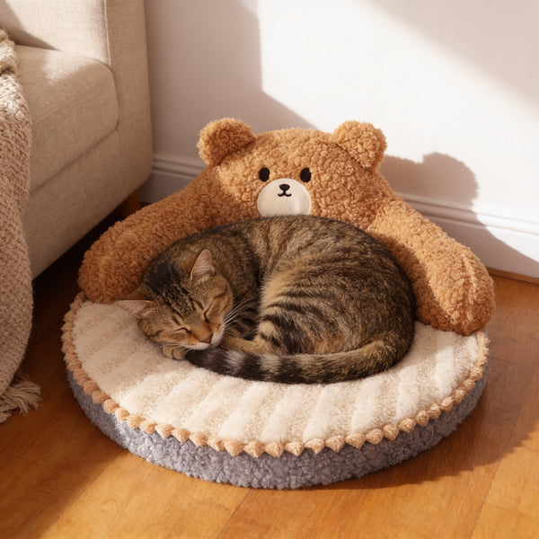 Tabby cat asleep on the round cat bed with a bear-shaped backrest and cream striped mat in a cosy living-room corner