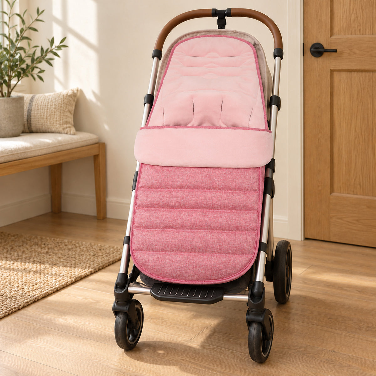Pink velvet-lined stroller footmuff on an empty stroller beside an oak bench in a warm entryway