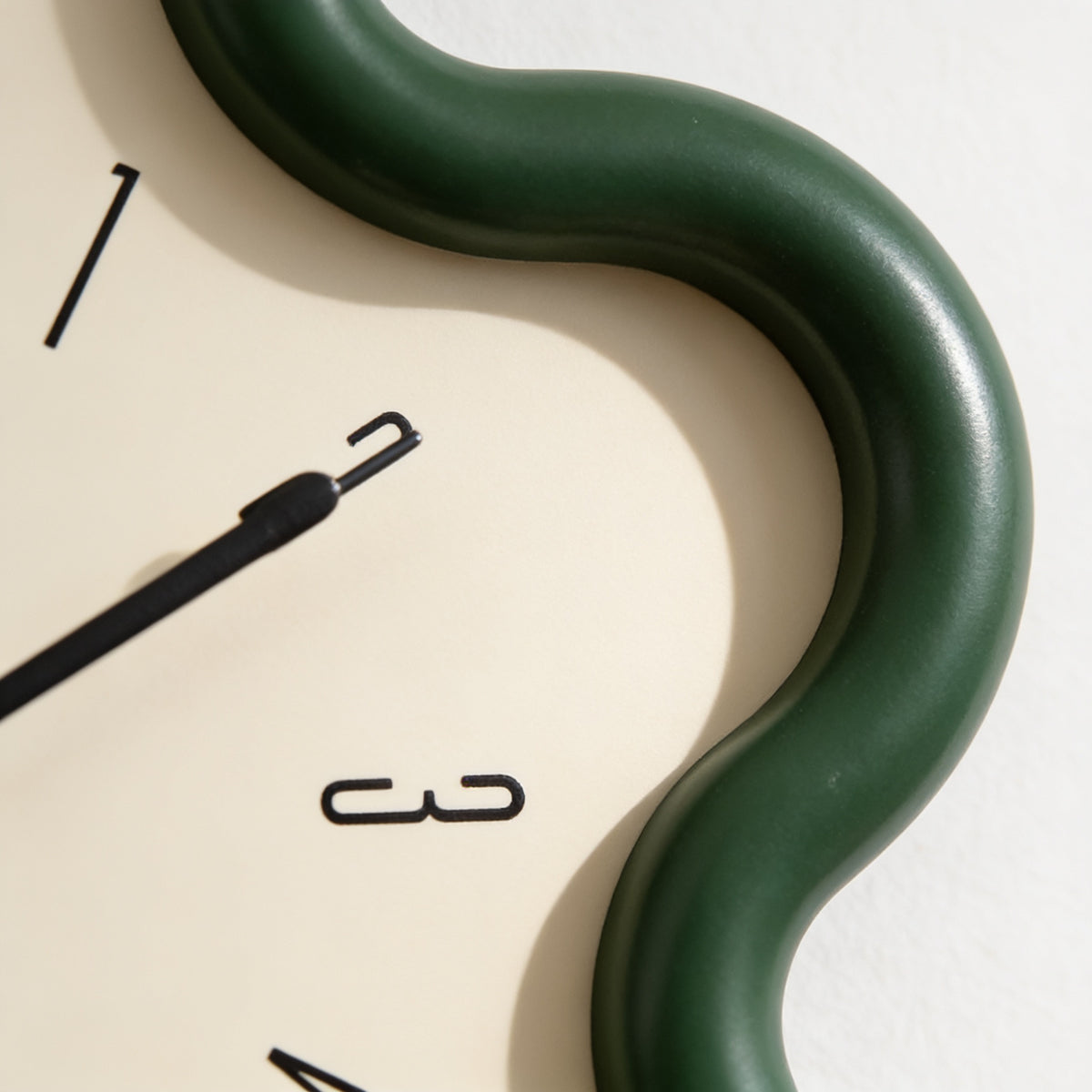 Close-up of the rounded green frame edge and cream dial — Wavy Flower-Shaped Wall Clock