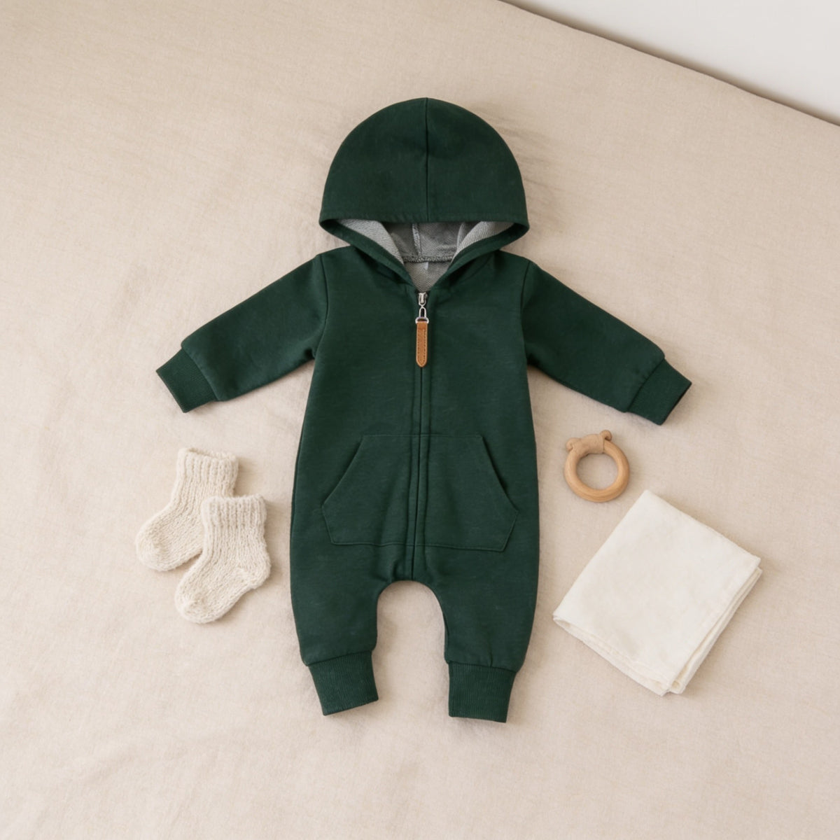 Forest Green zip-up hooded baby romper laid flat on a linen bedspread.
