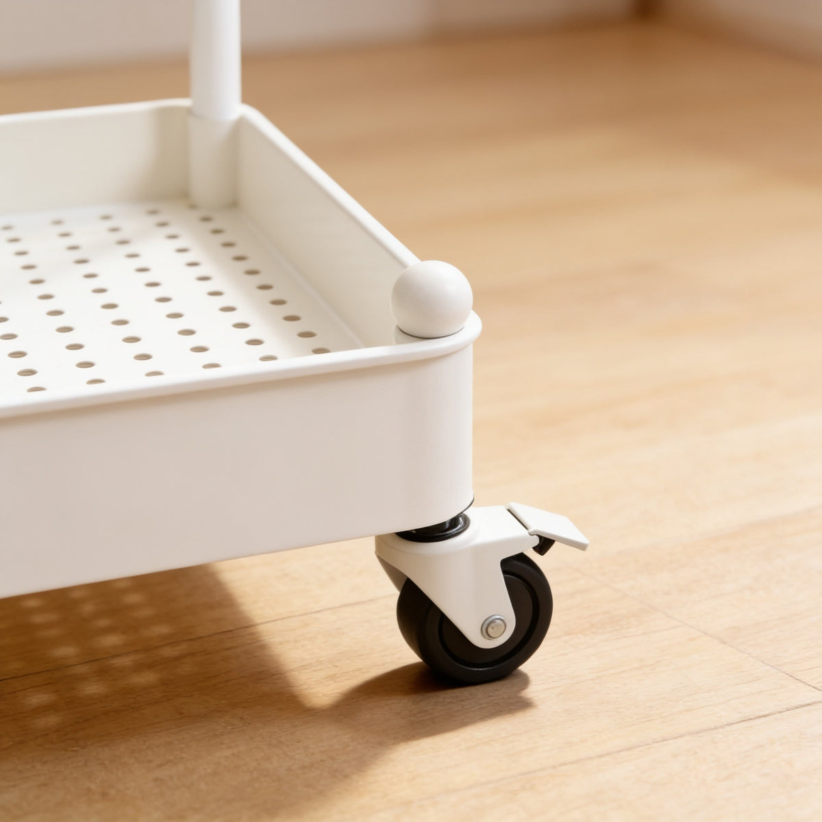 Close view of a swivel caster with a brake tab under the white cart's bottom tray.