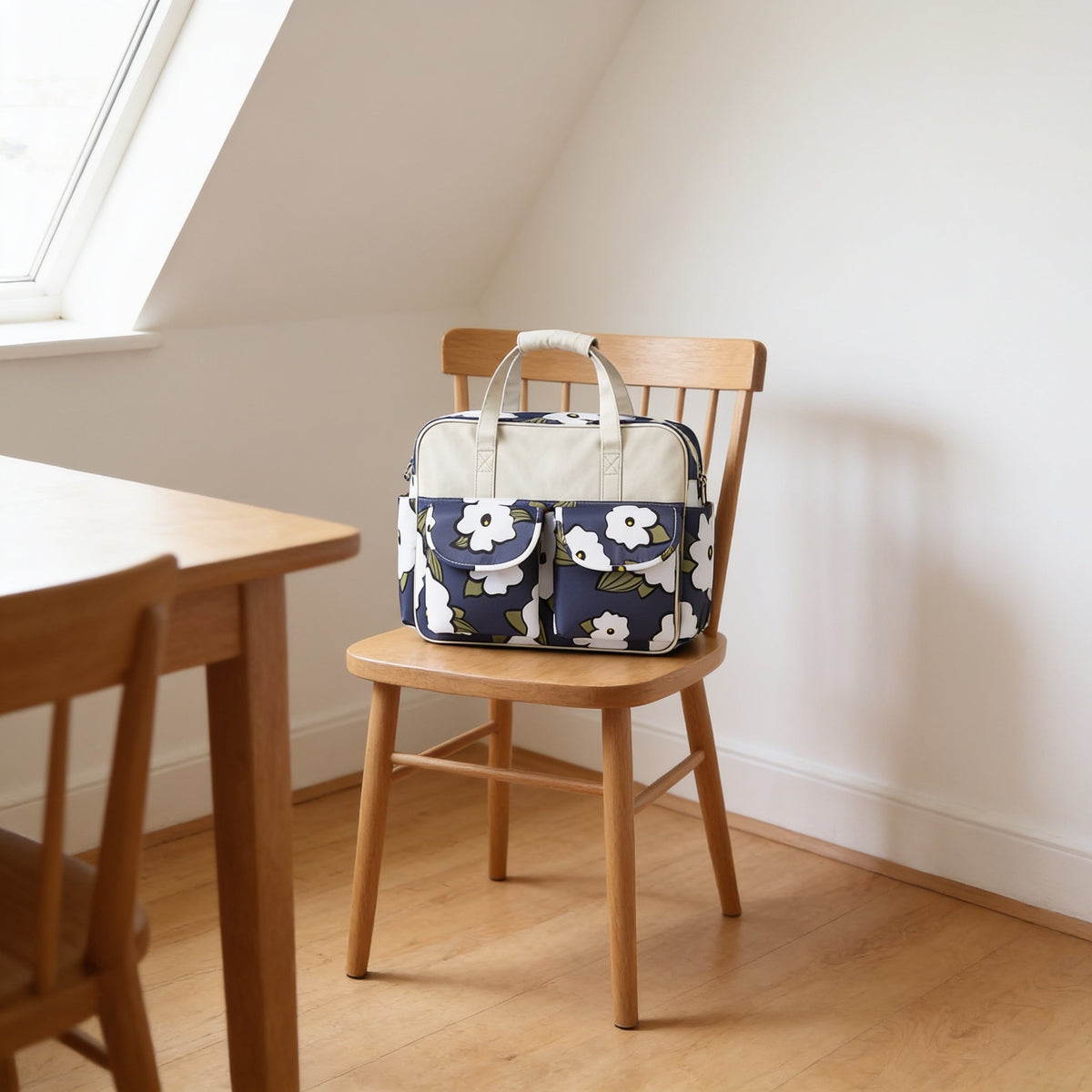 Navy floral diaper tote on a dining chair seat, nearly as wide as the 42 cm seat.