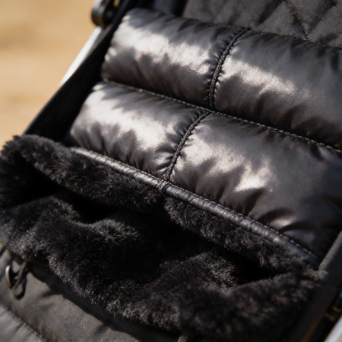 Close detail of the quilted black shell meeting the plush fleece lining.