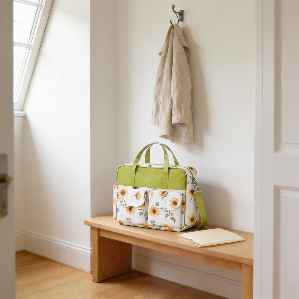 Sunflower print diaper tote bag on a light oak hallway bench, its changing mat folded beside it.