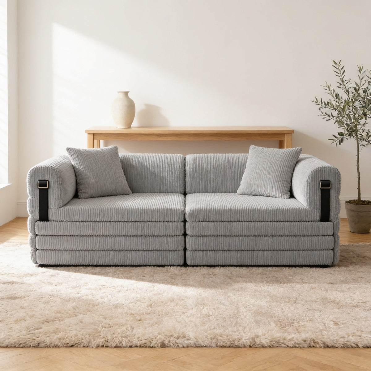 Light grey corduroy convertible sofa bed in sofa mode in a warm living room.