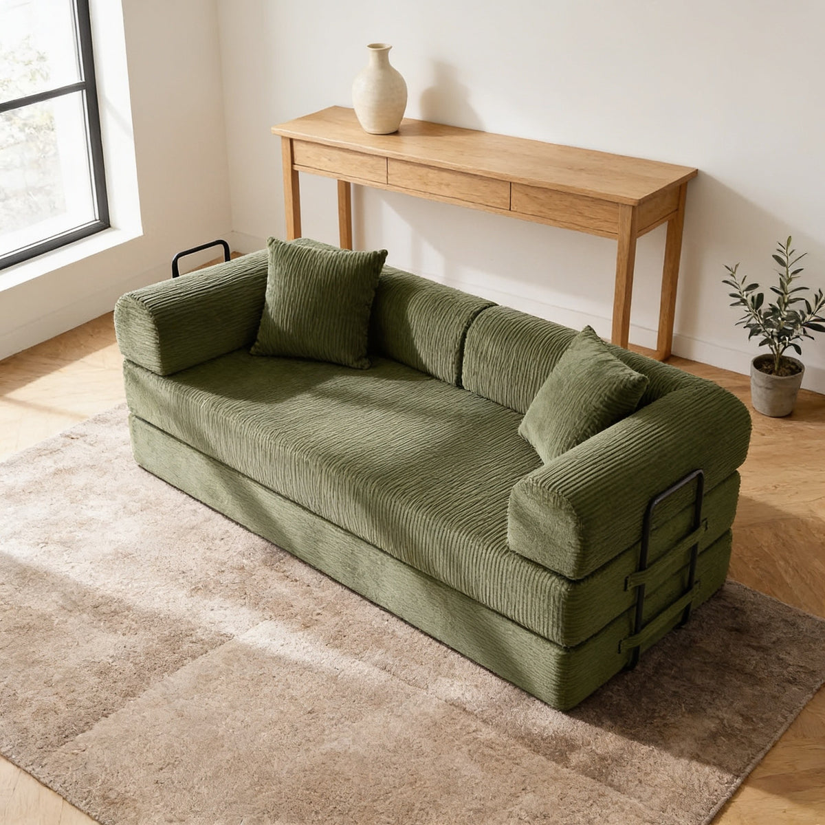 Olive green corduroy convertible sofa bed in sofa mode in a warm living room.