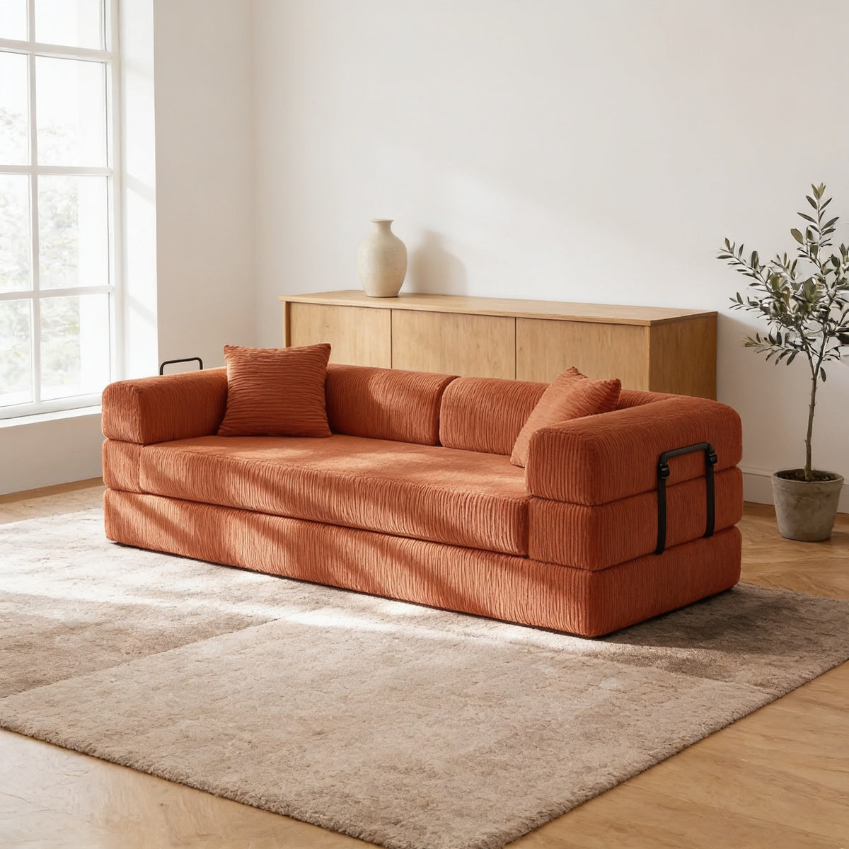 Burnt orange corduroy convertible sofa bed in sofa mode in a warm living room.