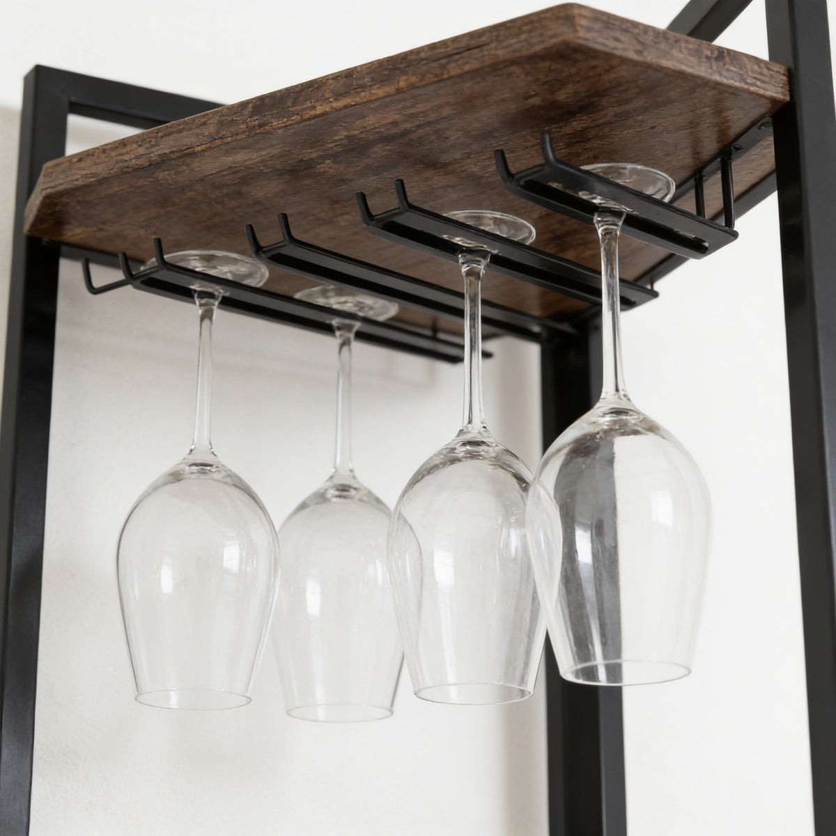Wine glasses hanging upside down from the black steel stemware rails fixed under the rack's top wood shelf.