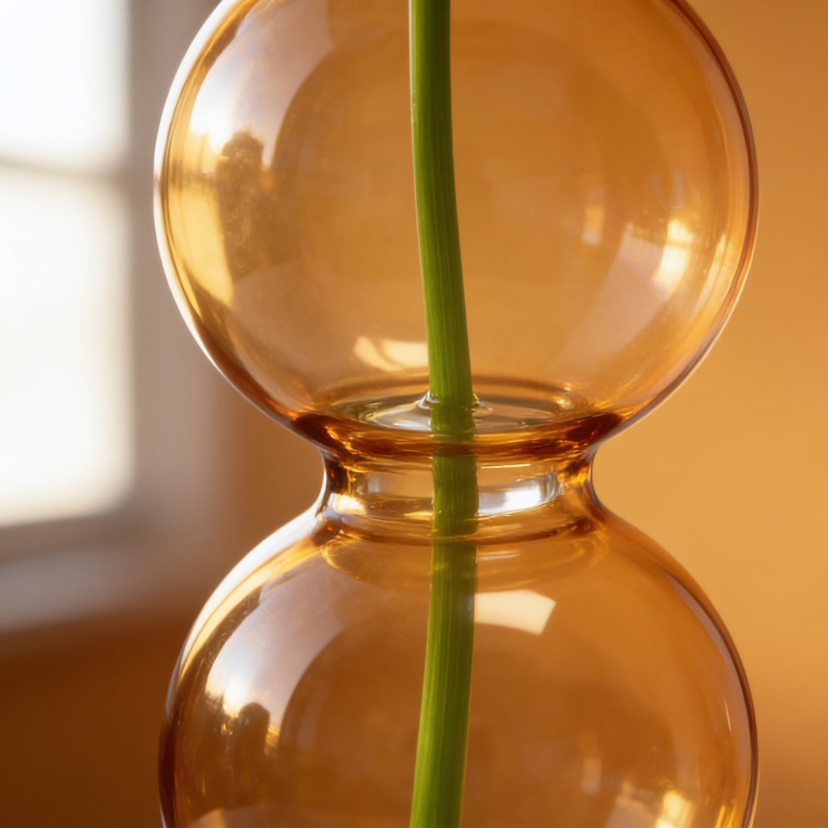 Close detail of two amber glass bubbles and the fused neck between them.
