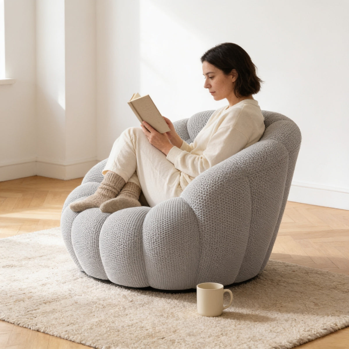 Adult sitting curled up deep inside the bubble armchair, reading, showing its one hundred and ten centimetre depth.