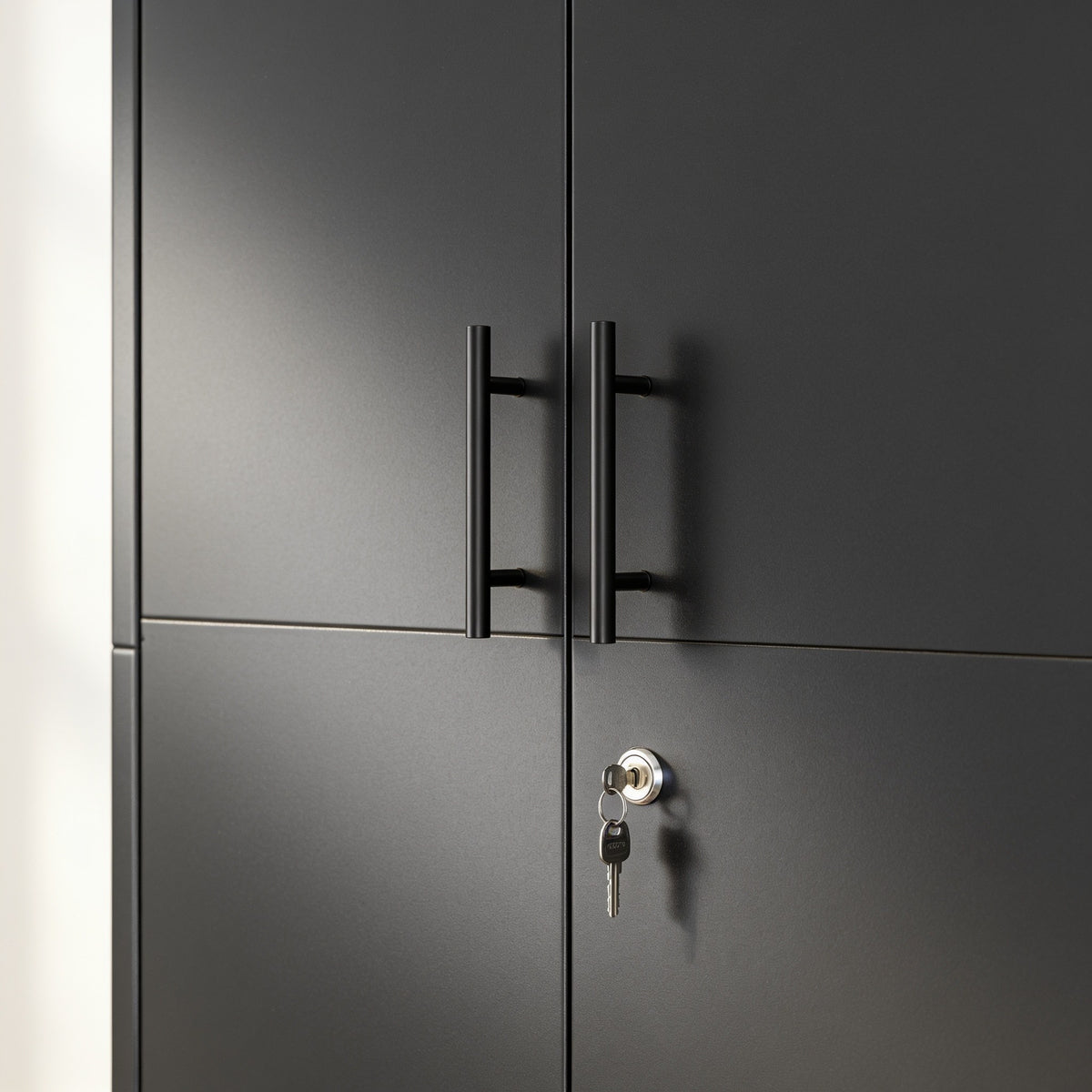 Close view of the storage cabinet's two black bar handles and the round lock cylinder with the key inserted.
